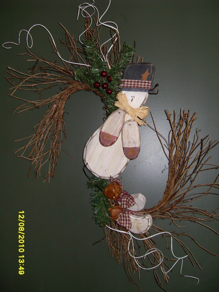 A wreath of twigs and branches with a snowman on it.