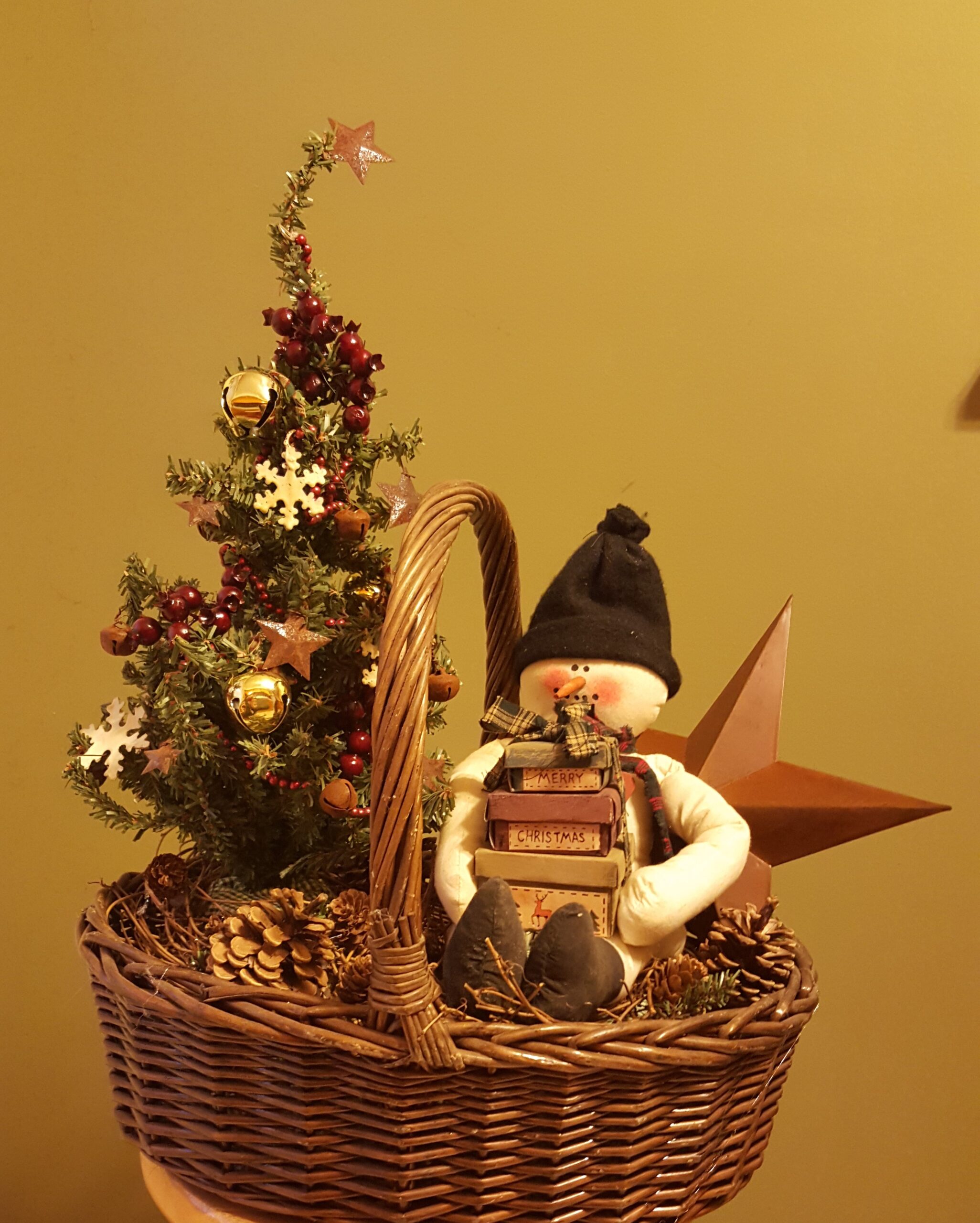 A basket with a snowman sitting on top of it.