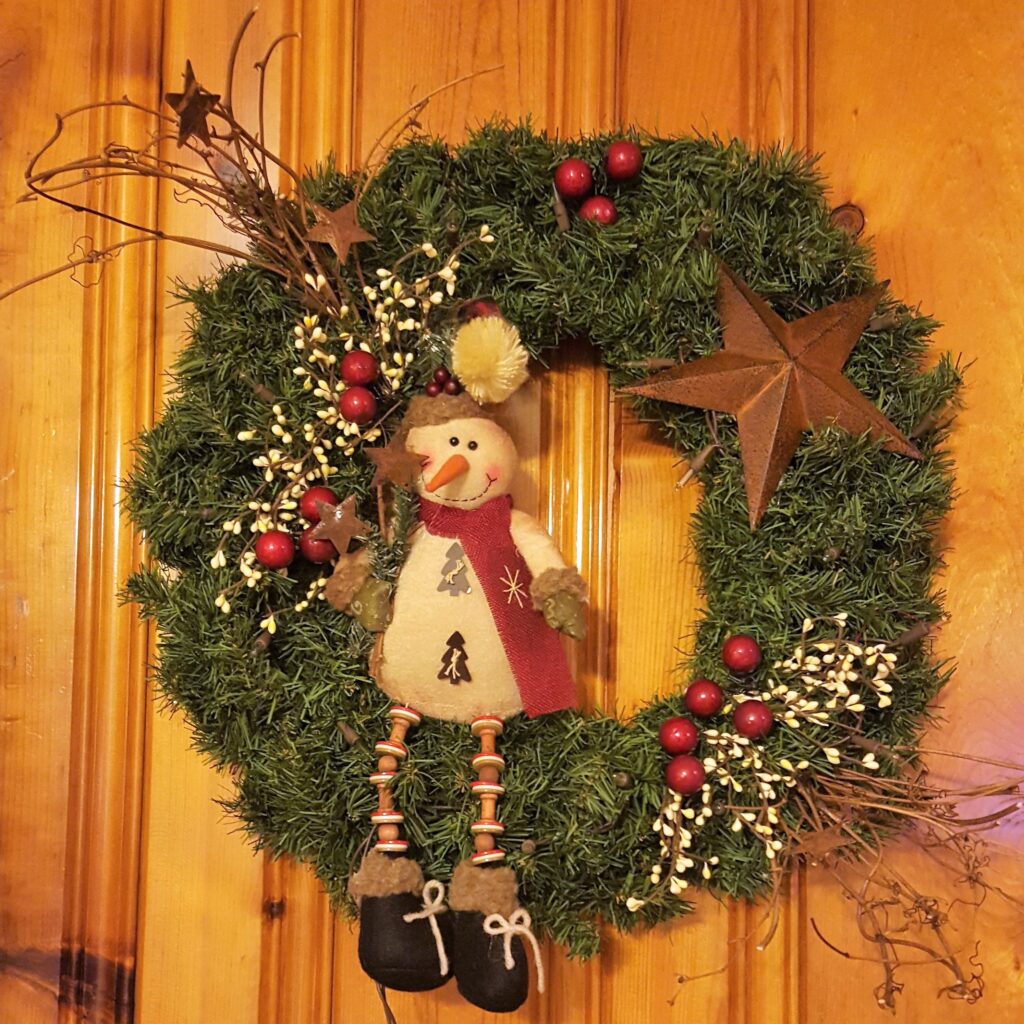 A wreath with a wooden figure hanging on it.