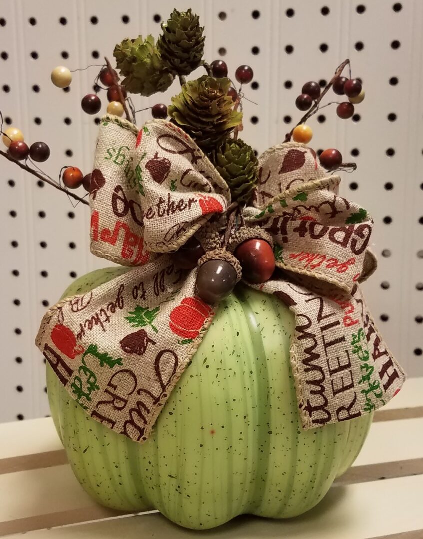 A green pumpkin with a bow on top of it.