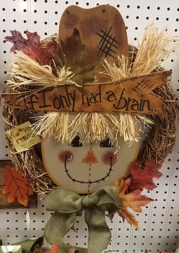 A scarecrow with a bow and leaves on it's head.