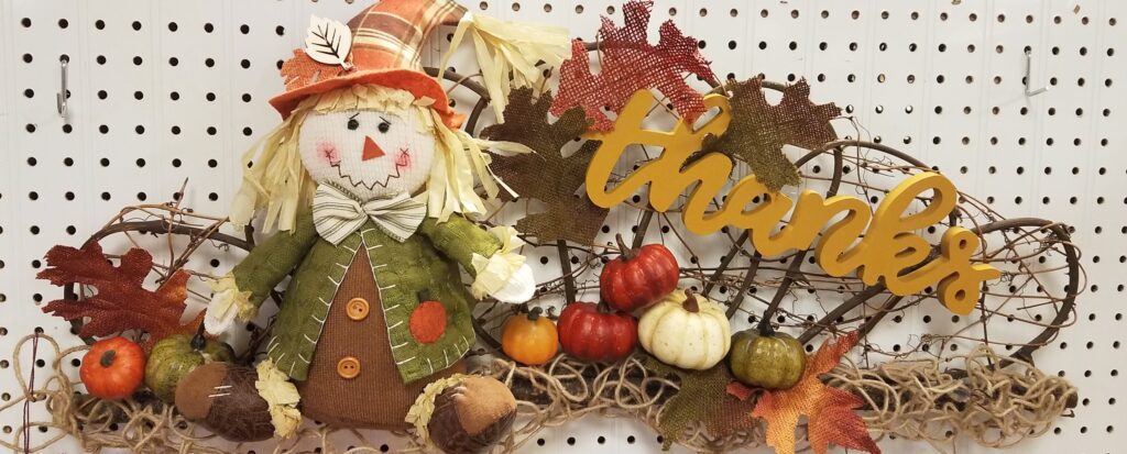 A close up of a scarecrow with leaves and pumpkins