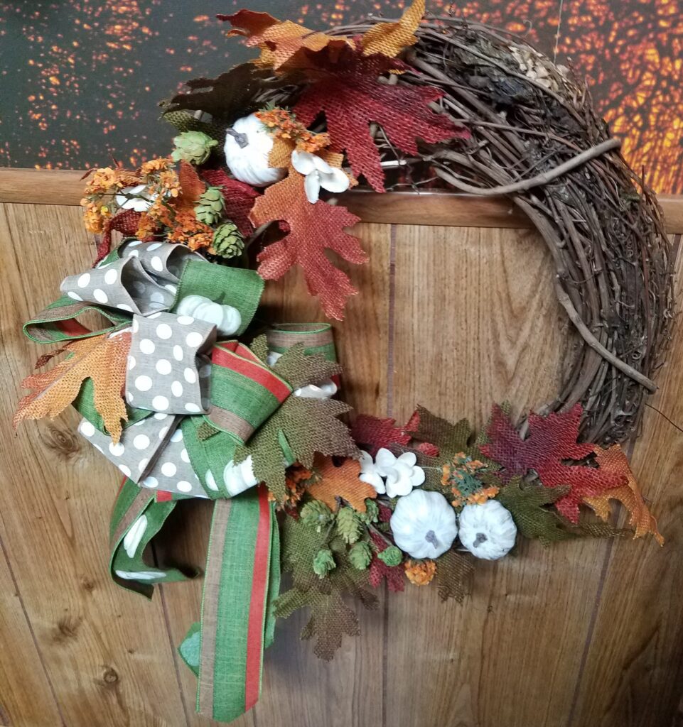 A wreath with leaves and birds on it.