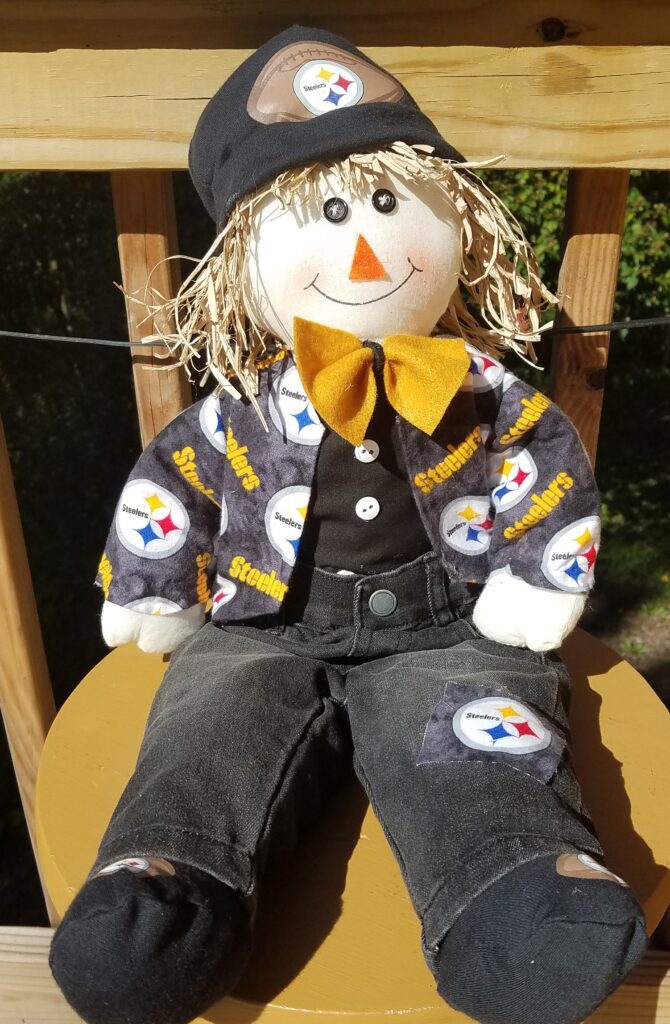 A stuffed scarecrow sitting on top of a chair.