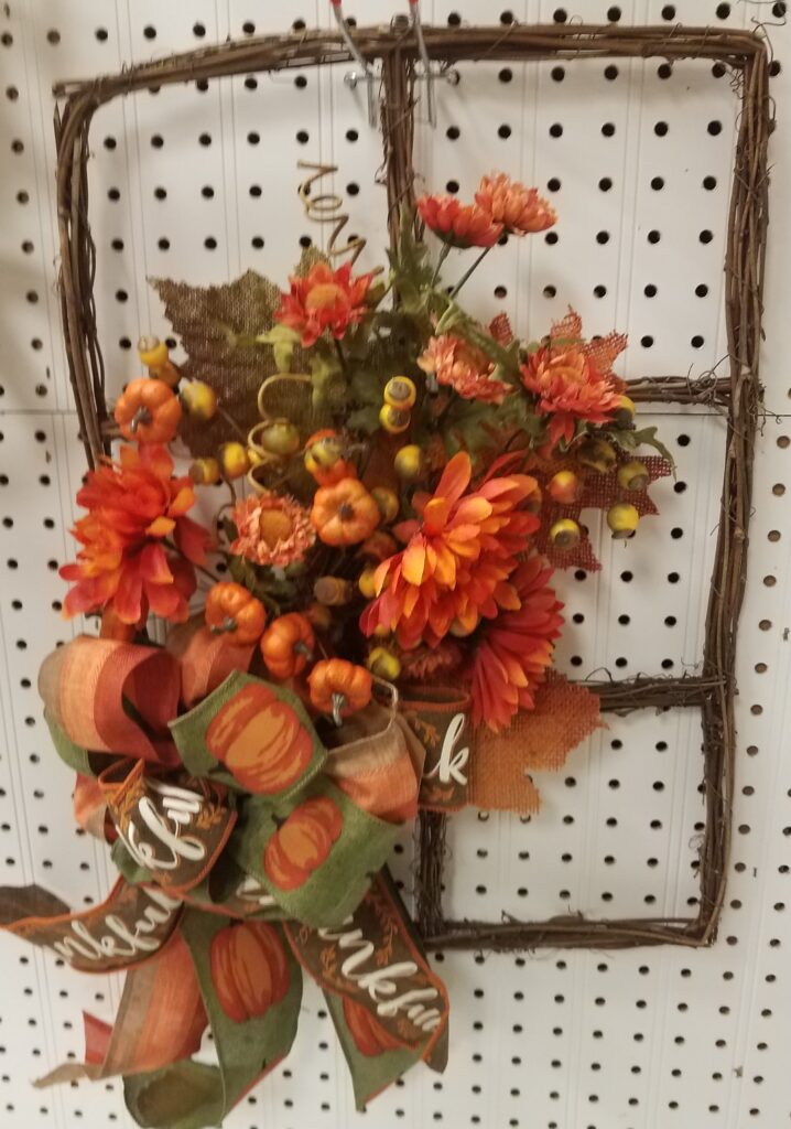 A fall wreath with orange flowers and leaves.