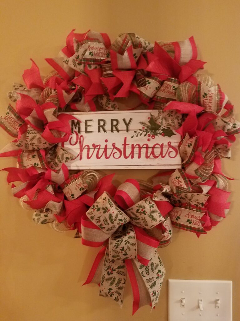 A christmas wreath with red and brown ribbons.