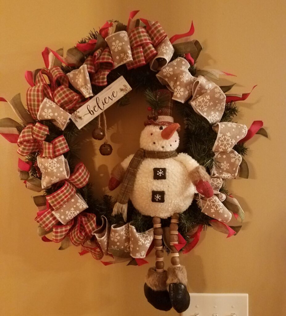 A wreath with a snowman hanging on the wall.