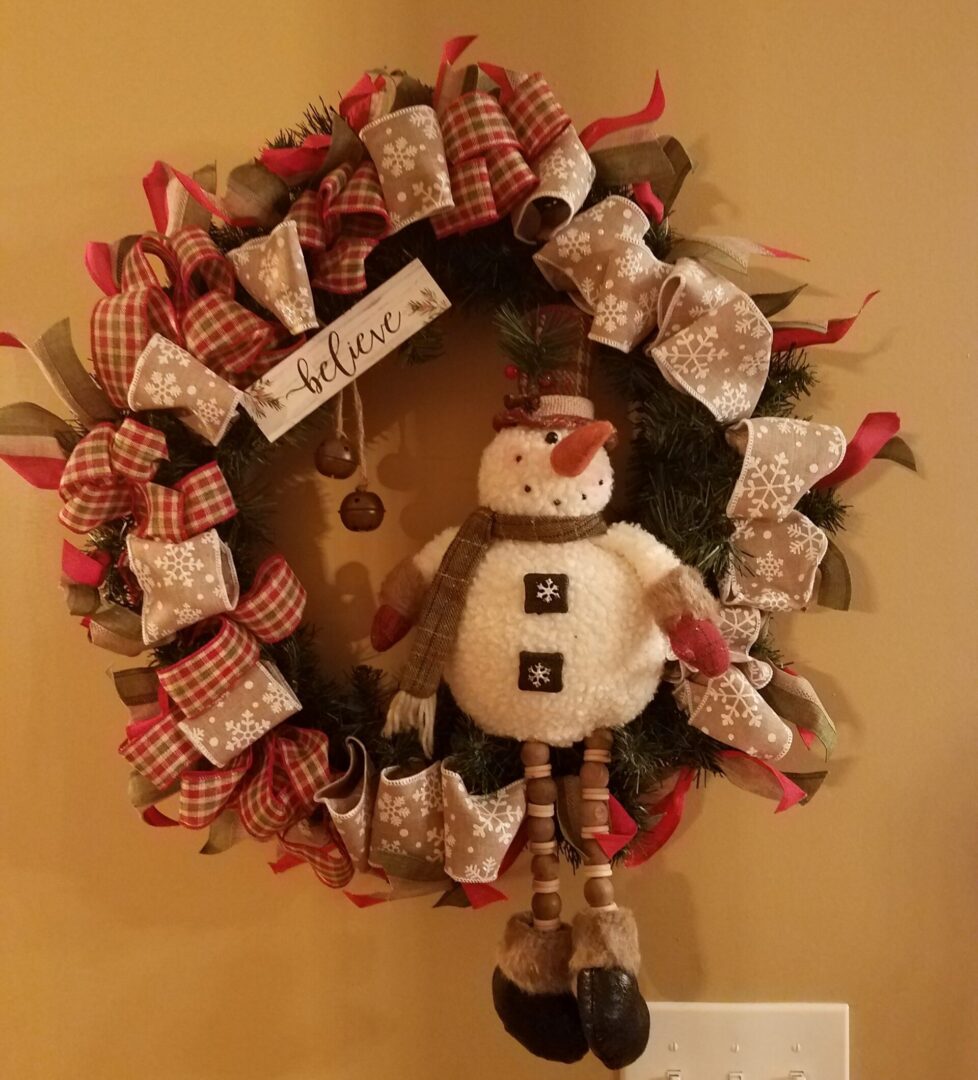 A wreath with a snowman hanging on the wall.