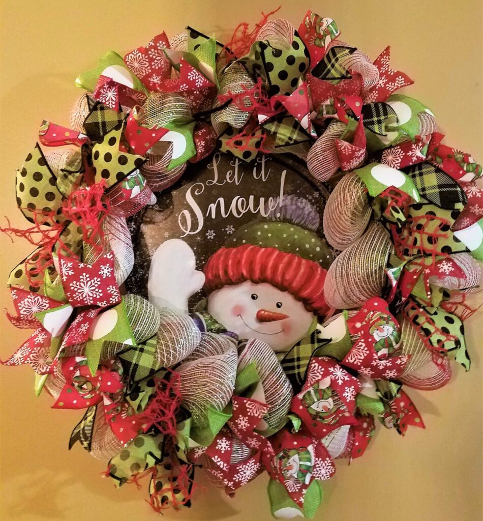 A wreath with a snowman on it is hanging up.