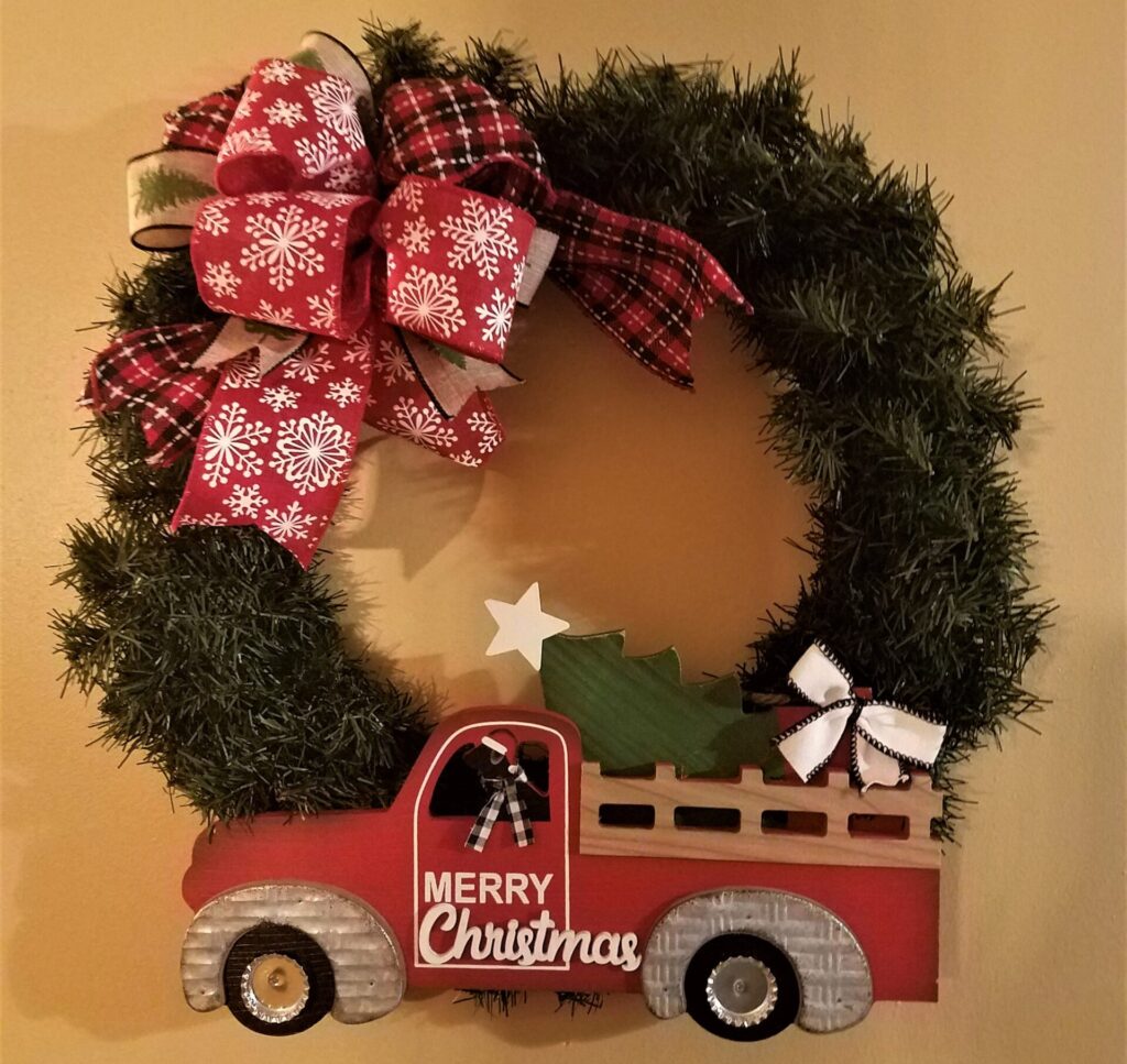 A wreath with a truck and christmas tree on it.