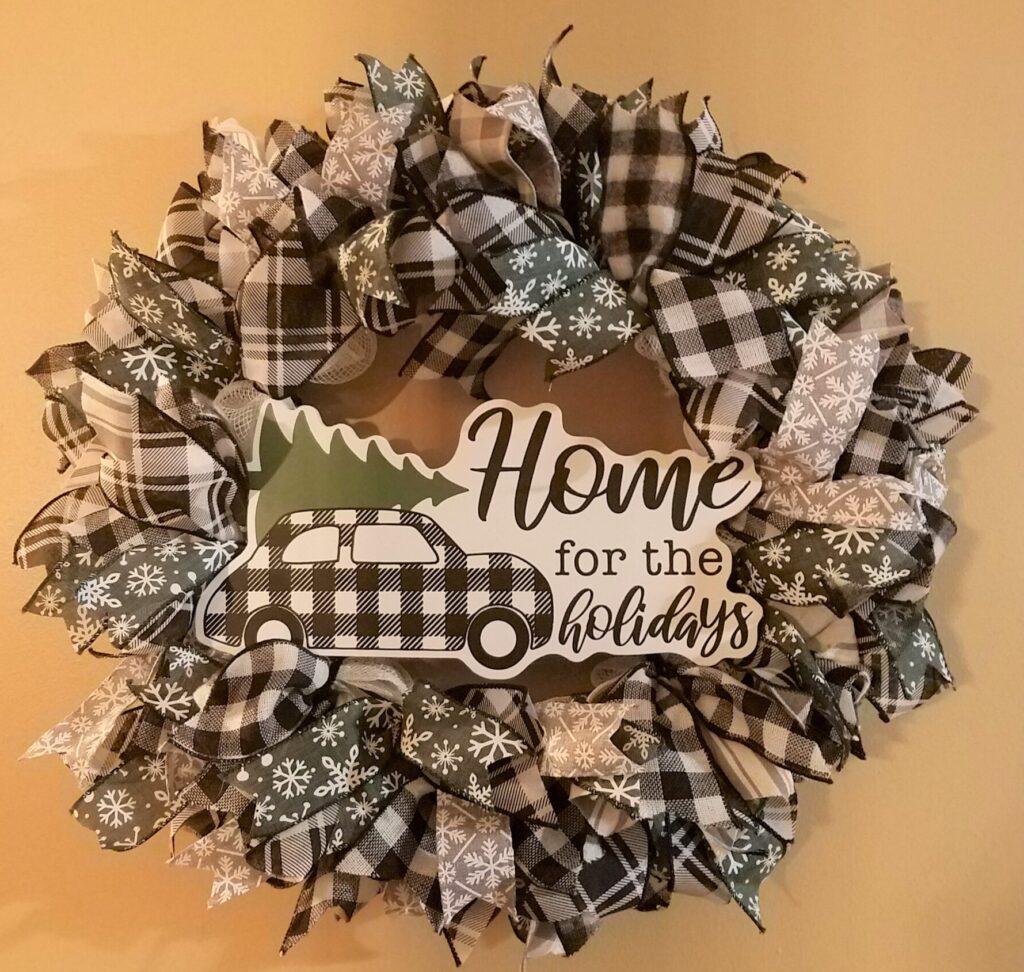 A wreath that has black and white plaid ribbon.