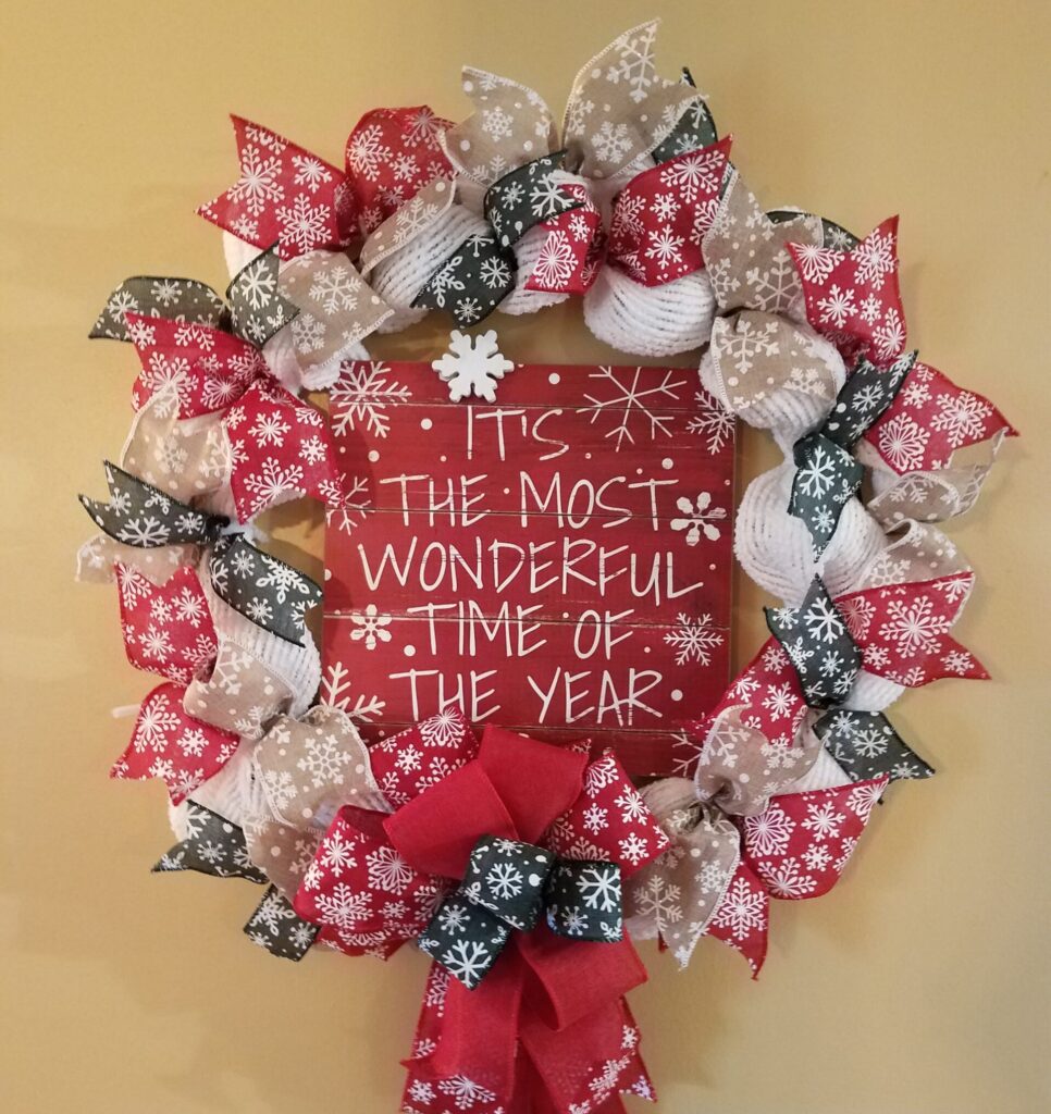 A christmas wreath with red, white and silver ribbons.