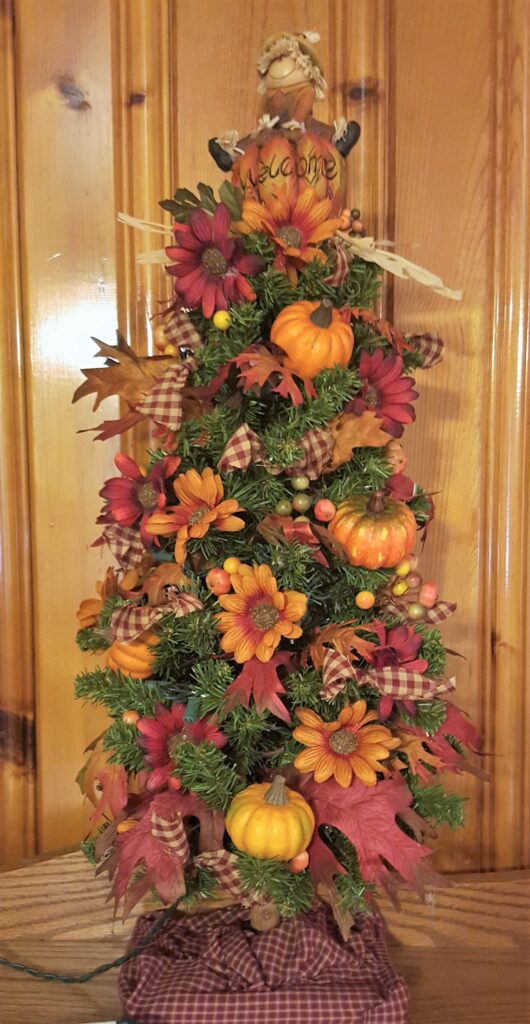 A decorated christmas tree with pumpkins and leaves.