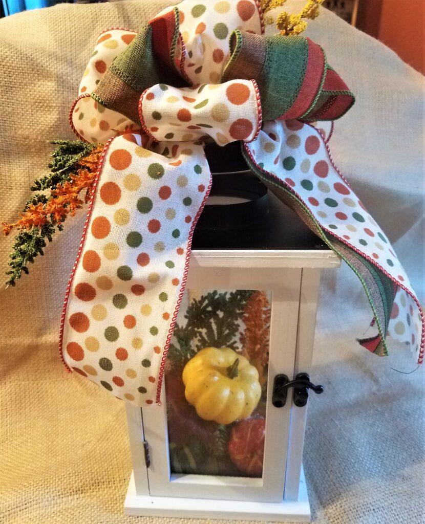 A decorative fall lantern with pumpkins and leaves.