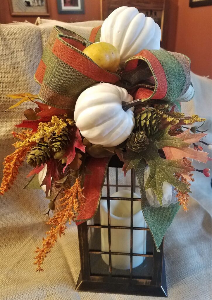 A vase with some pumpkins and leaves on it