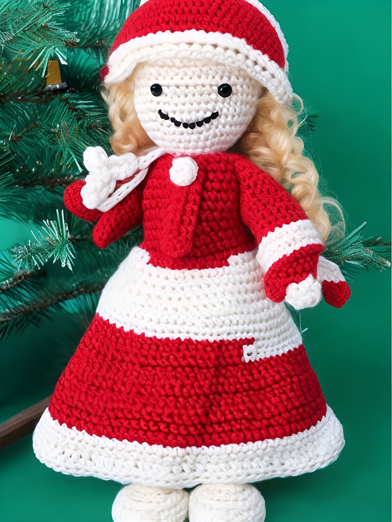 A crocheted doll in a red and white dress.