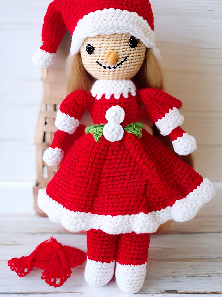 A crocheted doll in a red dress and hat.