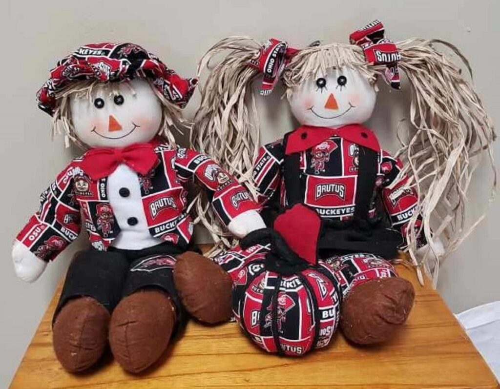 Two dolls sitting on top of a wooden table.