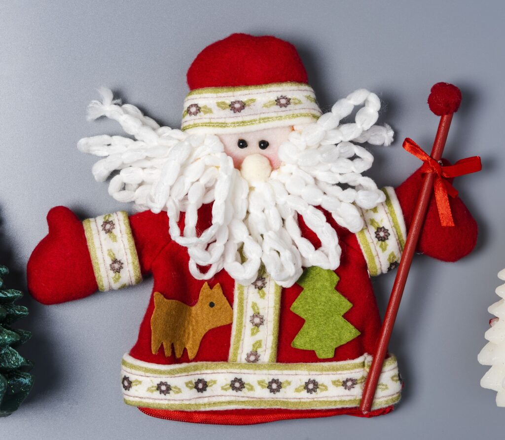 A santa clause ornament with a stick and tree.