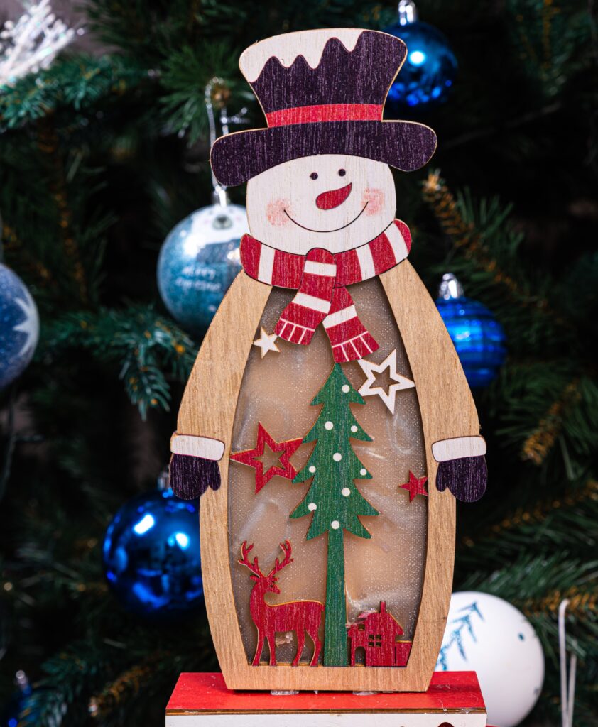 A wooden snowman ornament hanging on the tree.