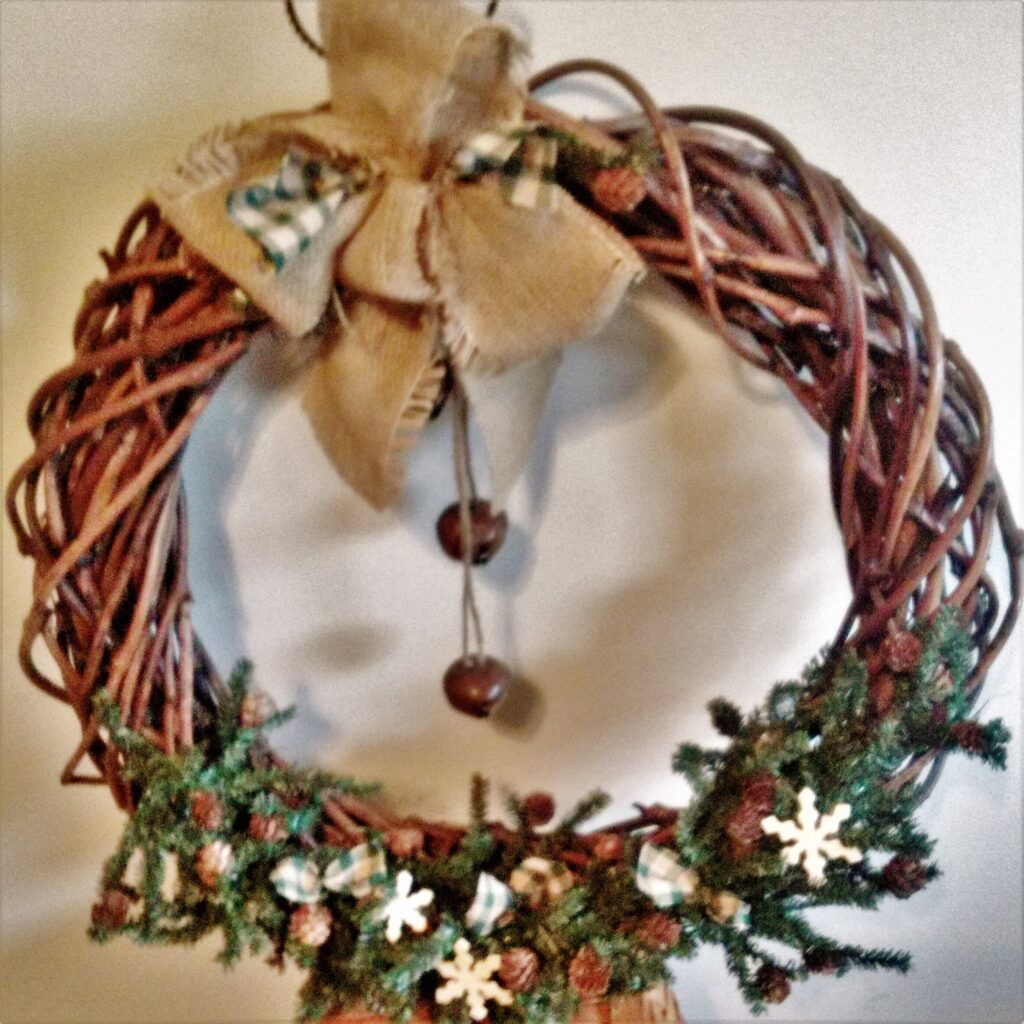 A wreath hanging on the wall with a bow and bells.