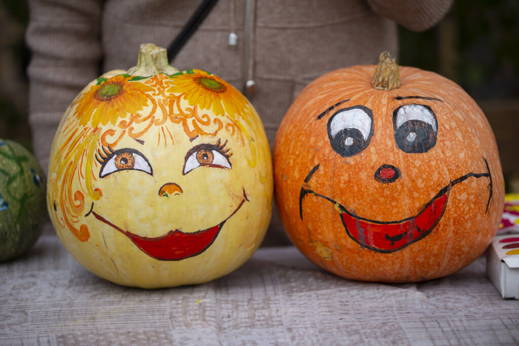 Two pumpkins with faces drawn on them sitting next to each other.