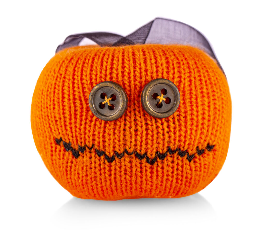 A knitted pumpkin with buttons and a ribbon.