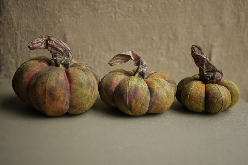 Three pumpkins are lined up against a wall.