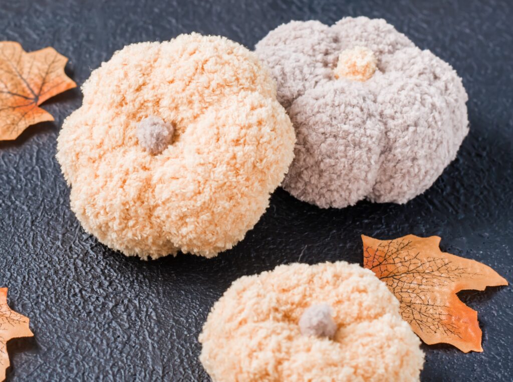 Three crocheted pumpkins sitting on top of a table.