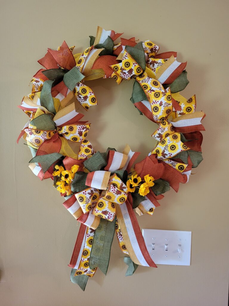 A wreath with ribbons and flowers on it.