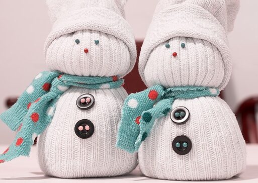 Two white snowmen with buttons and scarves on them.