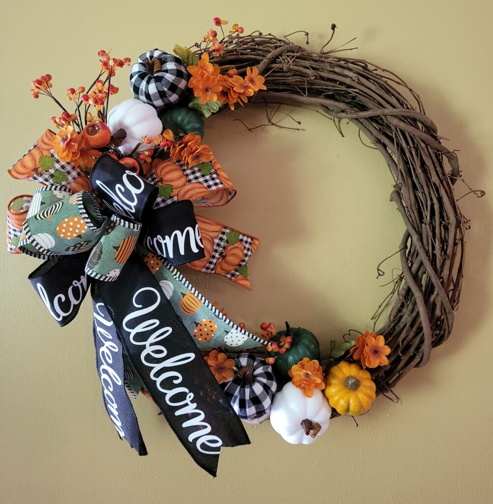 A wreath with flowers and ribbons on it.