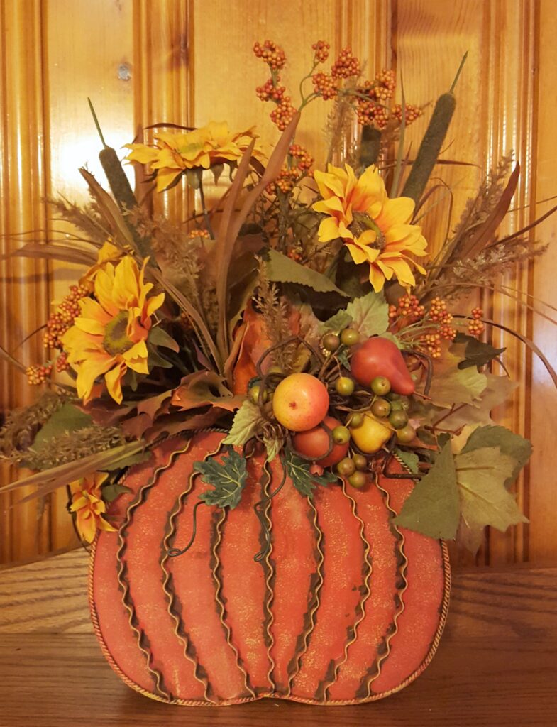 A pumpkin with flowers and apples in it