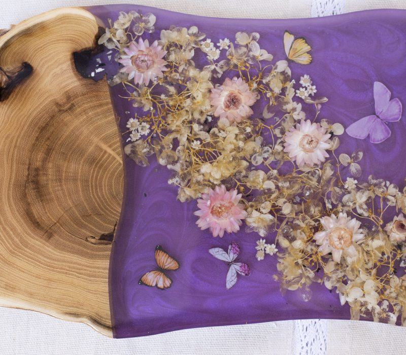 A wooden bowl with purple cloth and flowers on it.